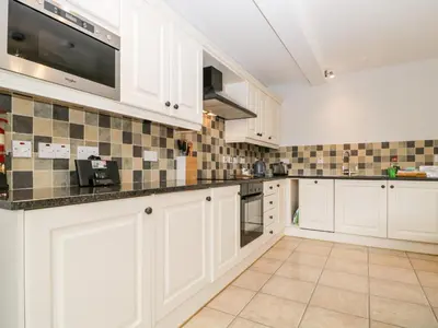 a kitchen with white cabinets and a tile floor at High Spy in Keswick