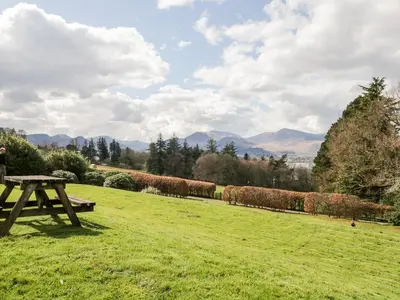 a picnic table in a field with mountains in the background at High Spy in Keswick