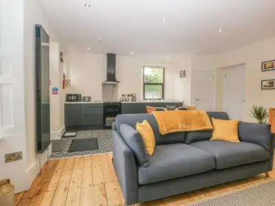 a living room with a blue couch and a kitchen at Hillcrest in Newton Stewart