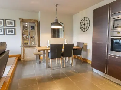 a dining room with a table and chairs and a clock at Apartment 1 St Mary's Church in Moffat