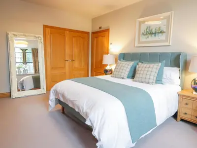a bedroom with a large bed and a mirror at Apartment 1 St Mary's Church in Moffat