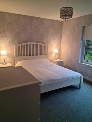 a bedroom with a white bed with two lamps at Cleughfoot House in Moffat