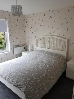 a bedroom with a white bed with a gray comforter at Cleughfoot House in Moffat