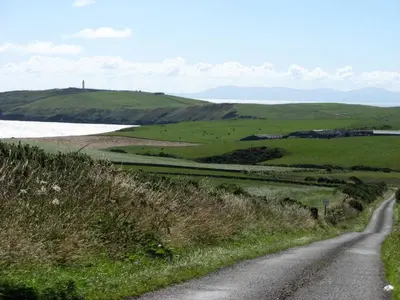 a road in the middle of a green field at Castlemoor Holiday Cottage, Mull of Galloway in Drummore