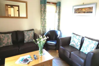 a living room with a couch and a table with flowers at Castlemoor Holiday Cottage, Mull of Galloway in Drummore