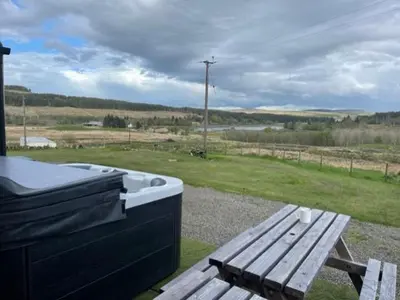 a hot tub and a picnic table with a bench at Carminnows Holiday Cottage in Carsphairn