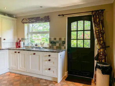 a kitchen with white cabinets and a black door at Geltsdale Garden Apartment ground floor home in Wetheral close to Carlisle & Ullswater in Wetheral