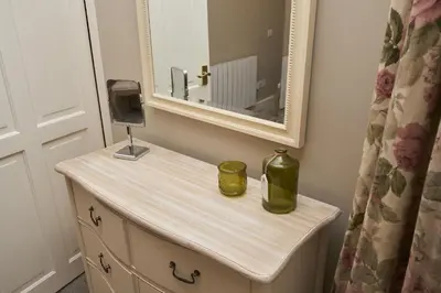 a bathroom vanity with a mirror and a green bottle on it at Old Bakers Cottage ground floor apartment centrally located in Grasmere with patio area in Grasmere