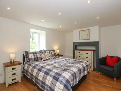 a bedroom with a bed and a chair at Low Melbecks House in Keswick