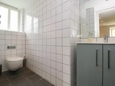 a white tiled bathroom with a toilet and a sink at Low Melbecks House in Keswick