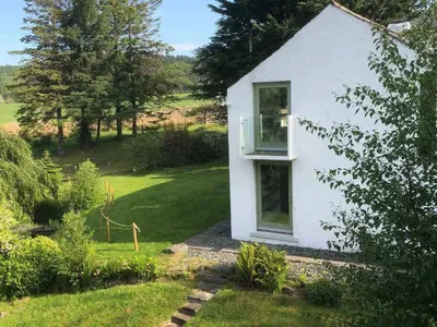a white house with a window in a garden at Low Melbecks House in Keswick