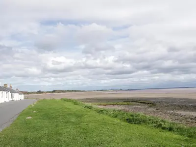 an empty road next to a beach with a house at 2 Whiterow in Powfoot