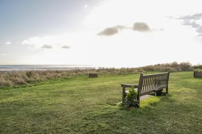 a park bench sitting in the grass near the ocean at 2 Whiterow in Powfoot