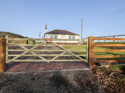 a wooden gate in front of a house at Glebe Cottage in Dumfries