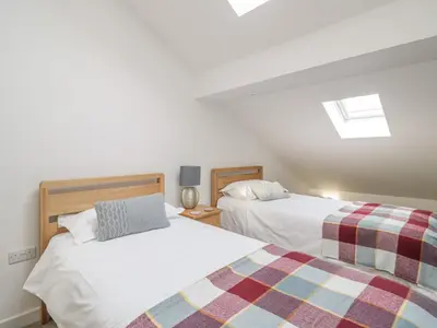 two beds in a room with white walls at Coney Garth Barn in Beckermet