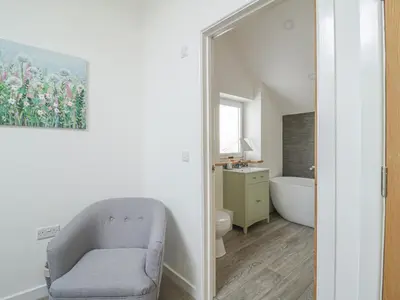 a bathroom with a chair and a bath tub at Coney Garth Barn in Beckermet