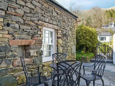 a group of chairs and a table in front of a stone building at Apple Barn in Applethwaite