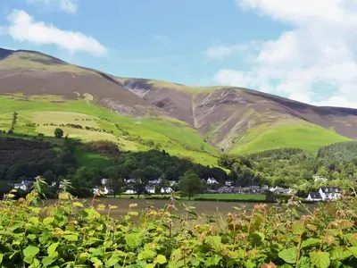 a green hillside with a village in the foreground at Apple Barn in Applethwaite