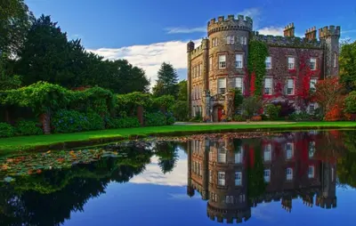 an old castle with its reflection in a lake at Cloncaird Castle Estate Cottages in Maybole