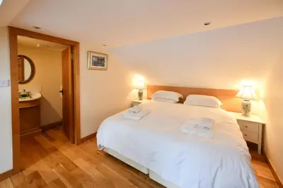 a bedroom with a white bed with two towels on it at Cloncaird Castle Estate Cottages in Maybole