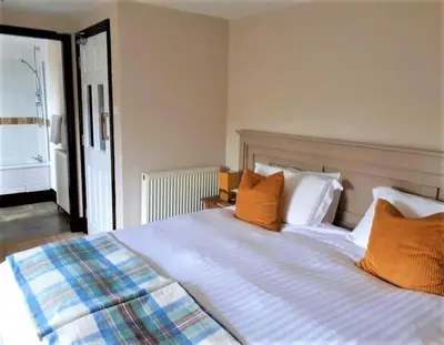 a bedroom with a bed with orange and white pillows at Corsewall Arms Guest House in Stranraer