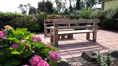a wooden bench sitting in a garden with flowers at Corsewall Arms Guest House in Stranraer
