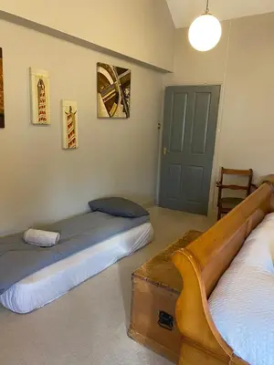 a room with two beds and a table and a door at Kezbah 1, 22 the square centre of Dalston village in Dalston