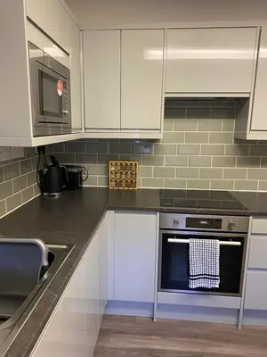 a kitchen with white cabinets and a stove top oven at Kezbah 1, 22 the square centre of Dalston village in Dalston