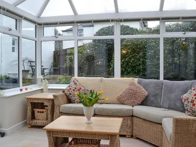 a conservatory with a couch and tables and windows at Apple Cross in Keswick