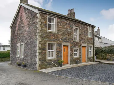 a brick house with orange doors on a street at Rowan House in Threlkeld