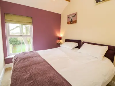 a bedroom with a large bed with a window at Tight Lyne Cottage in Carlisle