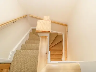 a staircase in a house with a wooden stair case at Tight Lyne Cottage in Carlisle