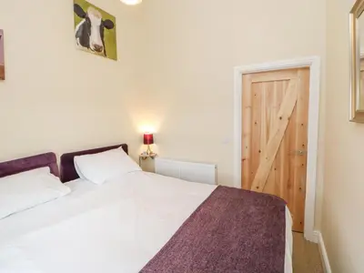 a bedroom with a white bed and a wooden door at Tight Lyne Cottage in Carlisle
