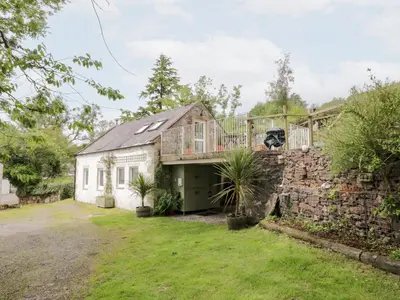 an exterior view of a house with a stone wall at The Barn in Dalbeattie