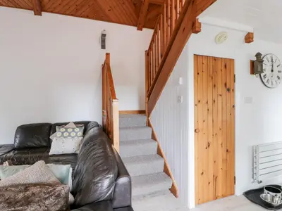 a living room with a leather couch and a staircase at The Barn in Dalbeattie