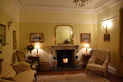 a living room with a fireplace and a mirror at Applegarth House in Lockerbie
