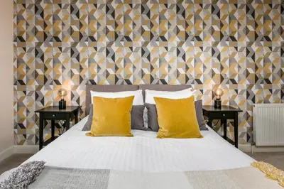 a bedroom with a bed with yellow pillows and two tables at The Lucas - Donnini Apartments in Ayr