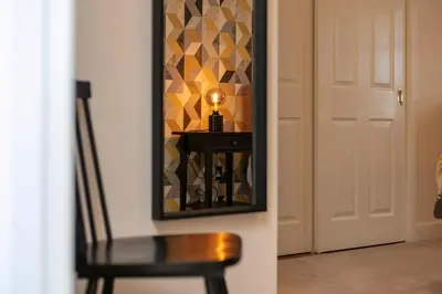 a mirror on a wall next to a table with a lamp at The Lucas - Donnini Apartments in Ayr