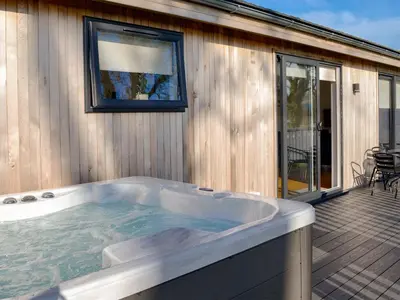 a jacuzzi tub on a deck next to a house at Cree Lodge - Uk13636 in Creetown