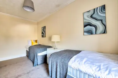 a bedroom with two beds and a painting on the wall at Oaktree Appartment Moffat in Moffat
