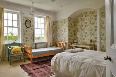 a bedroom with a bed and a chair and windows at Finest Retreats - Edwardian Country House - 9 Bed, Sleeping up to 21 in Longtown