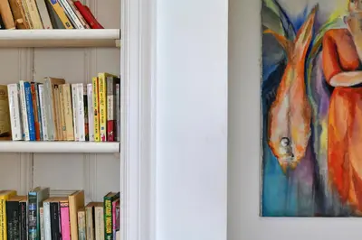 a book shelf filled with books next to a painting at Finest Retreats - Edwardian Country House - 9 Bed, Sleeping up to 21 in Longtown