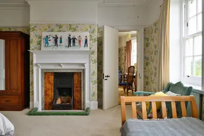 a living room with a fireplace with a picture on the wall at Finest Retreats - Edwardian Country House - 9 Bed, Sleeping up to 21 in Longtown