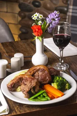 a plate of meat and vegetables with a glass of wine at Seacote Hotel in St Bees