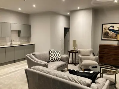 a living room with couches and chairs and a kitchen at Keswick Lake Road Apartments in Keswick