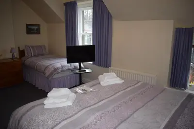 a bedroom with two beds and towels on the bed at Cragside Guest House in Keswick