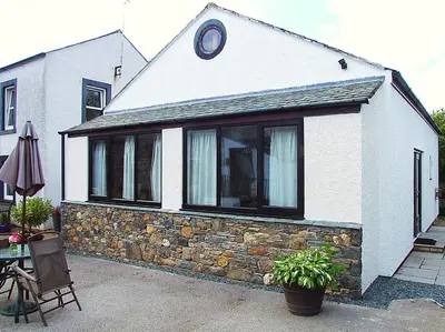a white house with a stone wall at Graysonside in Cockermouth