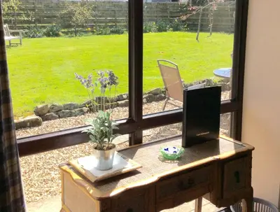 a window view of a garden with a desk in front of it at Graysonside in Cockermouth