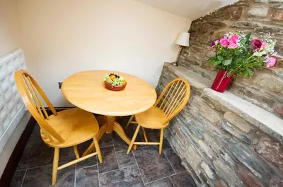 a wooden table with chairs and a vase with flowers at Graysonside in Cockermouth