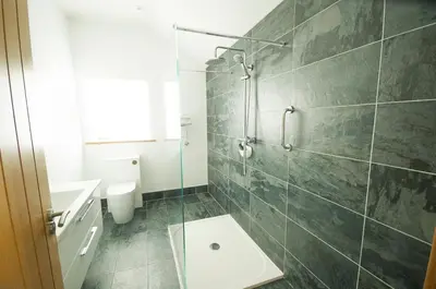 a bathroom with a shower and a toilet and a sink at Graysonside in Cockermouth